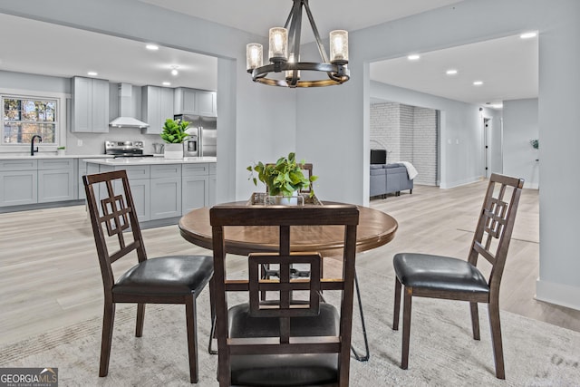 dining area with light hardwood / wood-style floors, sink, and a chandelier