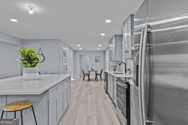 kitchen with sink, stainless steel appliances, gray cabinetry, and light hardwood / wood-style floors