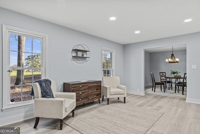 living area with light wood-type flooring, a wealth of natural light, and an inviting chandelier