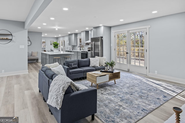 living room with light hardwood / wood-style flooring, french doors, and sink