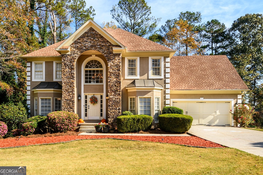 view of front of home featuring roof with shingles, stucco siding, a garage, driveway, and a front lawn