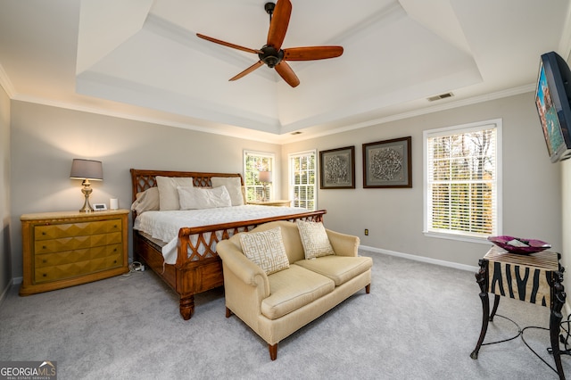 carpeted bedroom with a tray ceiling, ceiling fan, and crown molding