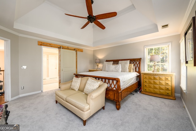 carpeted bedroom featuring ceiling fan, a barn door, a raised ceiling, and ornamental molding