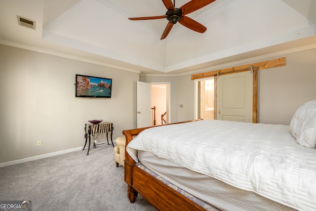 carpeted bedroom with connected bathroom, ceiling fan, a raised ceiling, a barn door, and ornamental molding