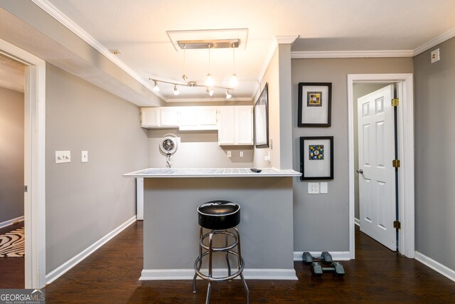 kitchen with hanging light fixtures, kitchen peninsula, crown molding, a kitchen bar, and white cabinets