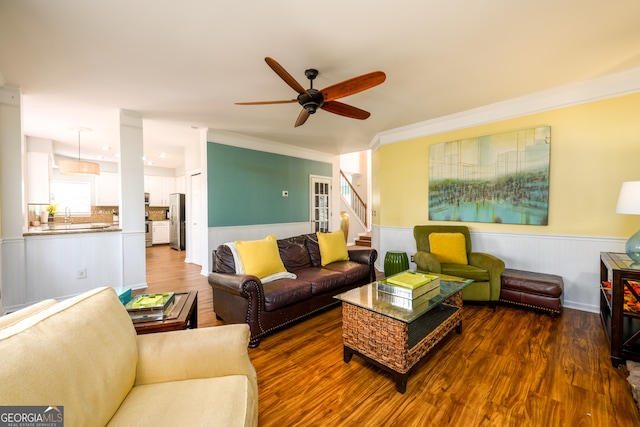 living room featuring dark hardwood / wood-style floors, ceiling fan, and ornamental molding