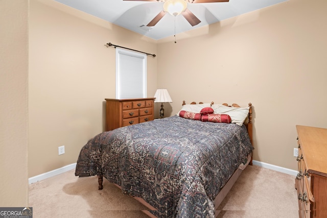 bedroom featuring light carpet, a ceiling fan, and baseboards