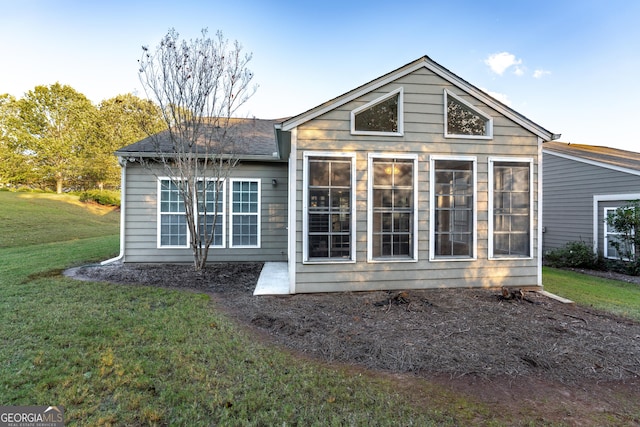 rear view of house with a sunroom and a lawn