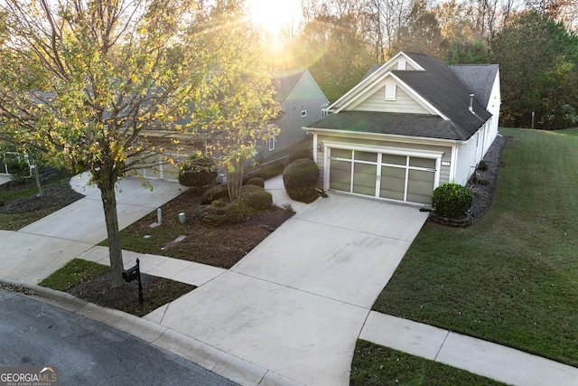 view of front of home with an attached garage, driveway, roof with shingles, and a front yard