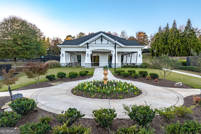 exterior space featuring curved driveway, a porch, a front yard, and fence