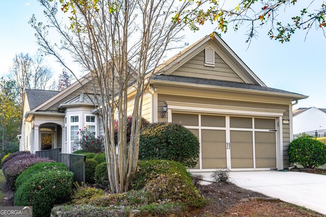 view of front of property with roof with shingles and concrete driveway