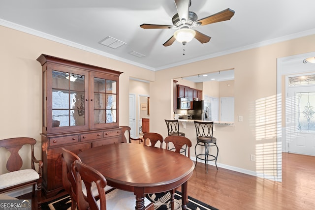 dining room with ceiling fan, a healthy amount of sunlight, light wood-style flooring, and crown molding