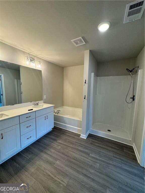 bathroom featuring vanity, hardwood / wood-style floors, and plus walk in shower