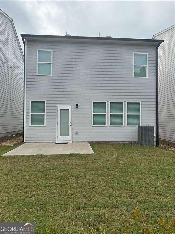 rear view of property featuring a patio area, a yard, and central AC