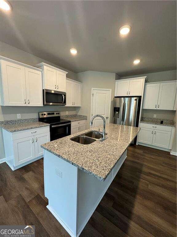 kitchen featuring stainless steel appliances, a kitchen island with sink, sink, dark hardwood / wood-style floors, and white cabinetry