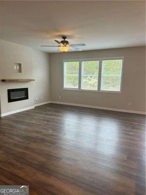 unfurnished living room with dark hardwood / wood-style floors, a healthy amount of sunlight, and ceiling fan