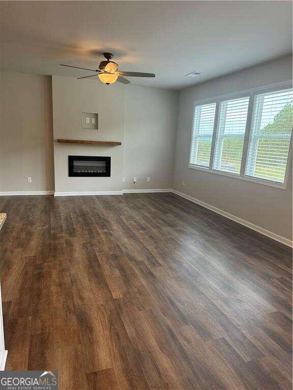 unfurnished living room featuring ceiling fan and dark hardwood / wood-style flooring