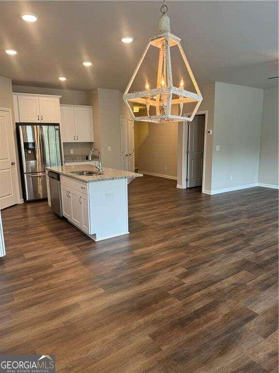 kitchen with appliances with stainless steel finishes, dark wood-type flooring, sink, a center island with sink, and white cabinetry