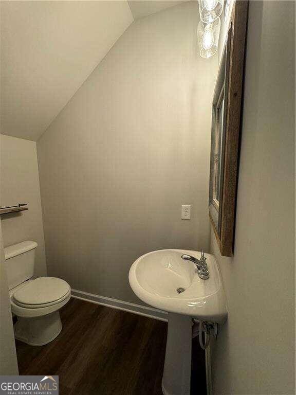 bathroom featuring sink, hardwood / wood-style floors, lofted ceiling, and toilet