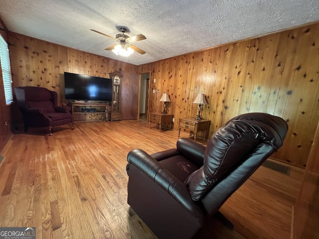 living room with ceiling fan, wood-type flooring, and a textured ceiling