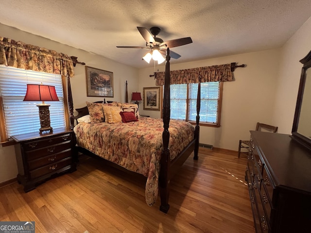 bedroom featuring hardwood / wood-style flooring, a textured ceiling, and ceiling fan