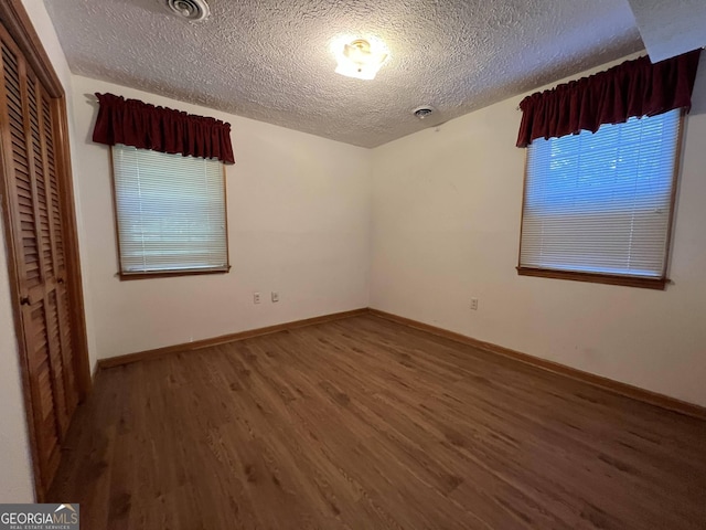 unfurnished bedroom featuring hardwood / wood-style flooring, a closet, and a textured ceiling