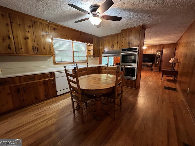 dining area with hardwood / wood-style flooring, ceiling fan, and wooden walls