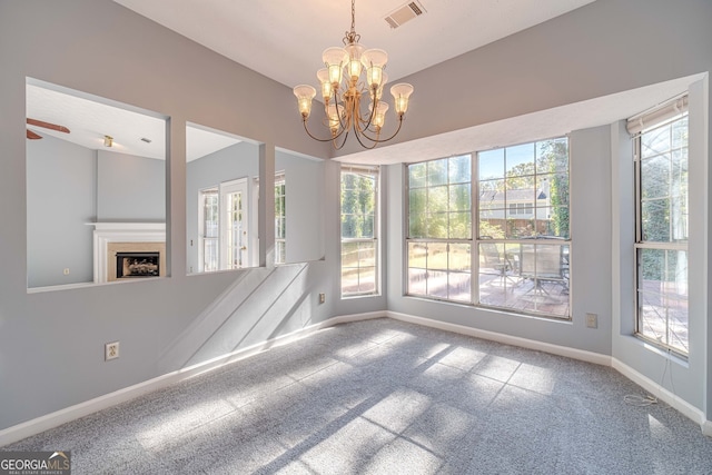 unfurnished dining area featuring carpet flooring, ceiling fan with notable chandelier, and a healthy amount of sunlight