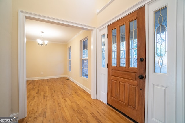 entryway with a chandelier, light hardwood / wood-style floors, and ornamental molding