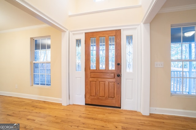 foyer with crown molding, plenty of natural light, and light hardwood / wood-style flooring