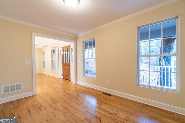 empty room with a wealth of natural light, light hardwood / wood-style floors, and ornamental molding