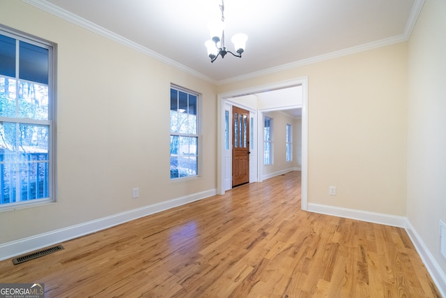 spare room featuring light hardwood / wood-style floors, crown molding, and a notable chandelier