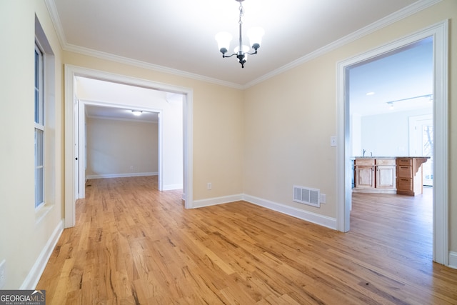 unfurnished dining area with light hardwood / wood-style floors, crown molding, and an inviting chandelier