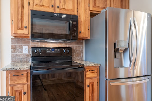 kitchen featuring black appliances, light stone countertops, and backsplash