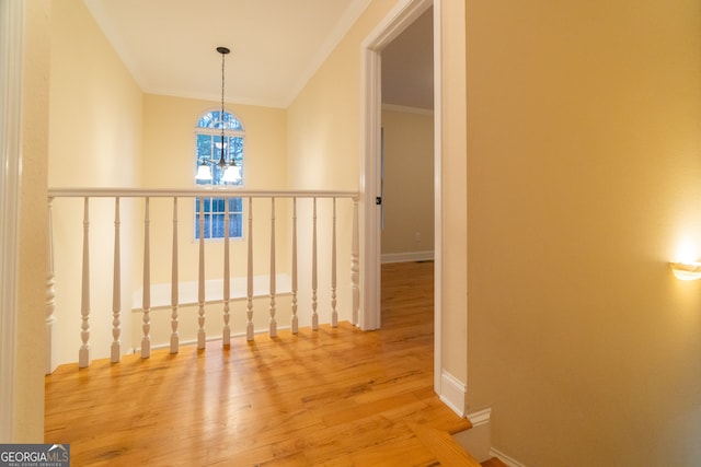 hallway with hardwood / wood-style flooring, crown molding, and an inviting chandelier