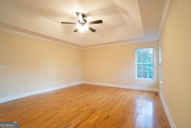 spare room with a raised ceiling, ceiling fan, light wood-type flooring, and ornamental molding