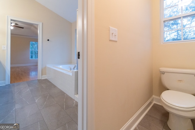 bathroom with toilet, tile patterned floors, a relaxing tiled tub, and vaulted ceiling