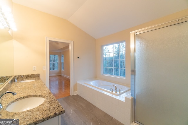 bathroom featuring separate shower and tub, hardwood / wood-style floors, vanity, and vaulted ceiling