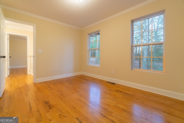 unfurnished room with plenty of natural light, light hardwood / wood-style floors, and ornamental molding