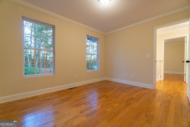 empty room with a wealth of natural light, light hardwood / wood-style flooring, and crown molding