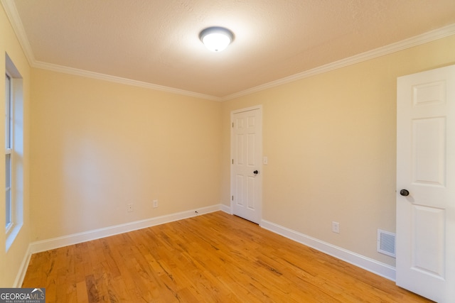 empty room featuring crown molding, hardwood / wood-style floors, and a textured ceiling