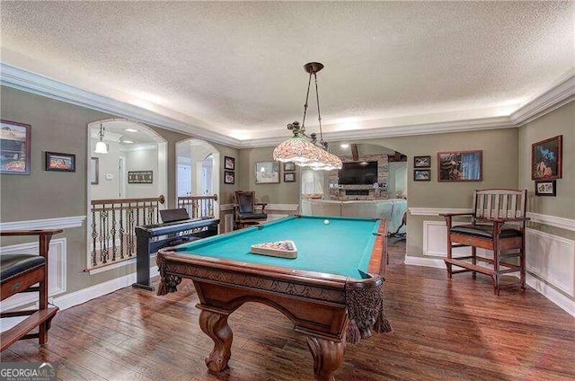 game room with dark hardwood / wood-style flooring, a textured ceiling, ornamental molding, and billiards