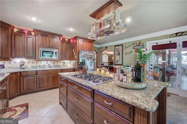 kitchen featuring backsplash, ornamental molding, a textured ceiling, stainless steel appliances, and light tile patterned floors