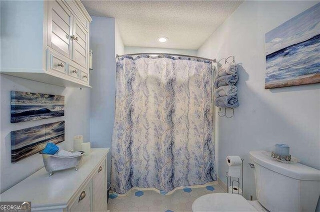 bathroom with a textured ceiling, toilet, and curtained shower