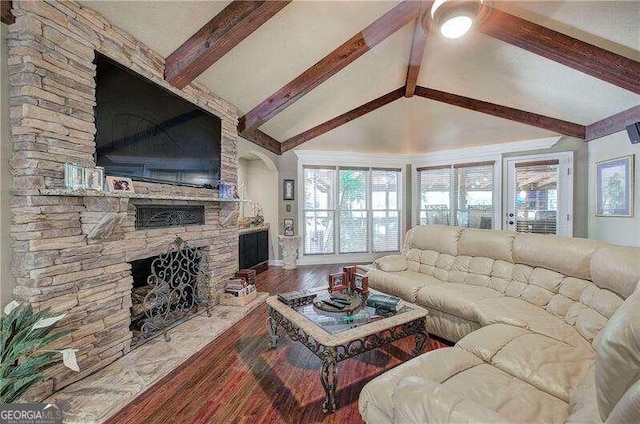 living room featuring vaulted ceiling with beams, wood-type flooring, a fireplace, and a wealth of natural light