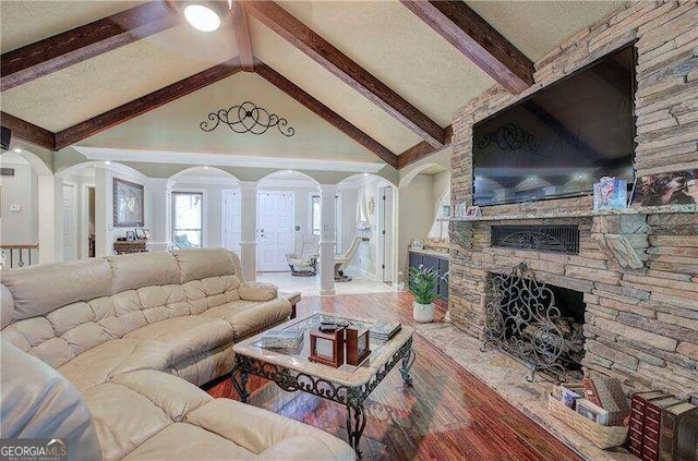 living room featuring hardwood / wood-style floors, vaulted ceiling with beams, ornate columns, and a fireplace