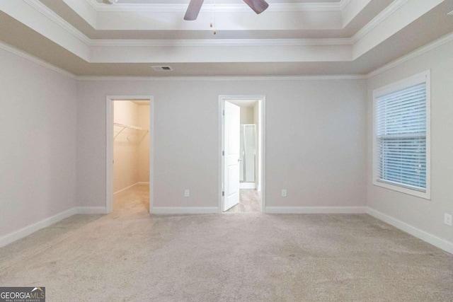 unfurnished bedroom with a spacious closet, ceiling fan, light carpet, a closet, and ornamental molding