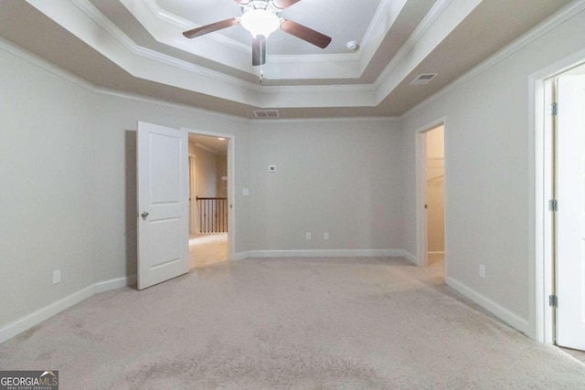 unfurnished bedroom featuring ceiling fan, a raised ceiling, ornamental molding, and light carpet