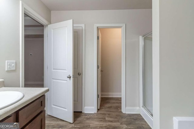 bathroom with hardwood / wood-style floors, vanity, and an enclosed shower