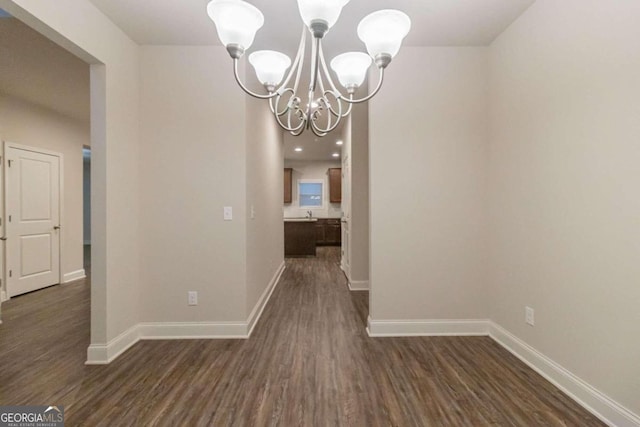 unfurnished dining area featuring a chandelier and dark hardwood / wood-style floors